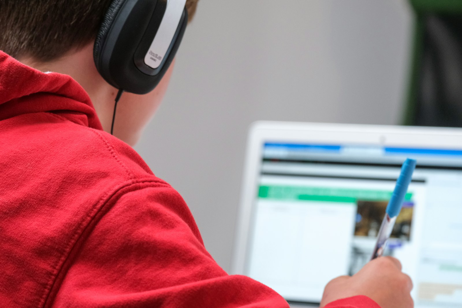 Image d'illustration — un élève suit un cours à distance sur son ordinateur portable, casque sur les oreilles.