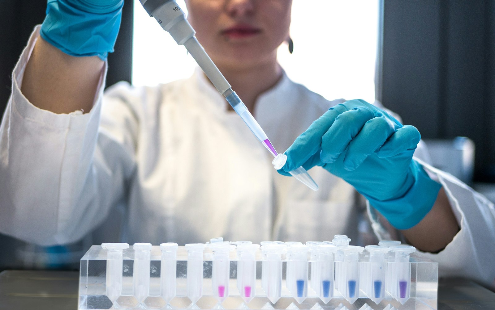 Image d'illustration — une chercheuse manipule des échantillons chimiques colorés au laboratoire.